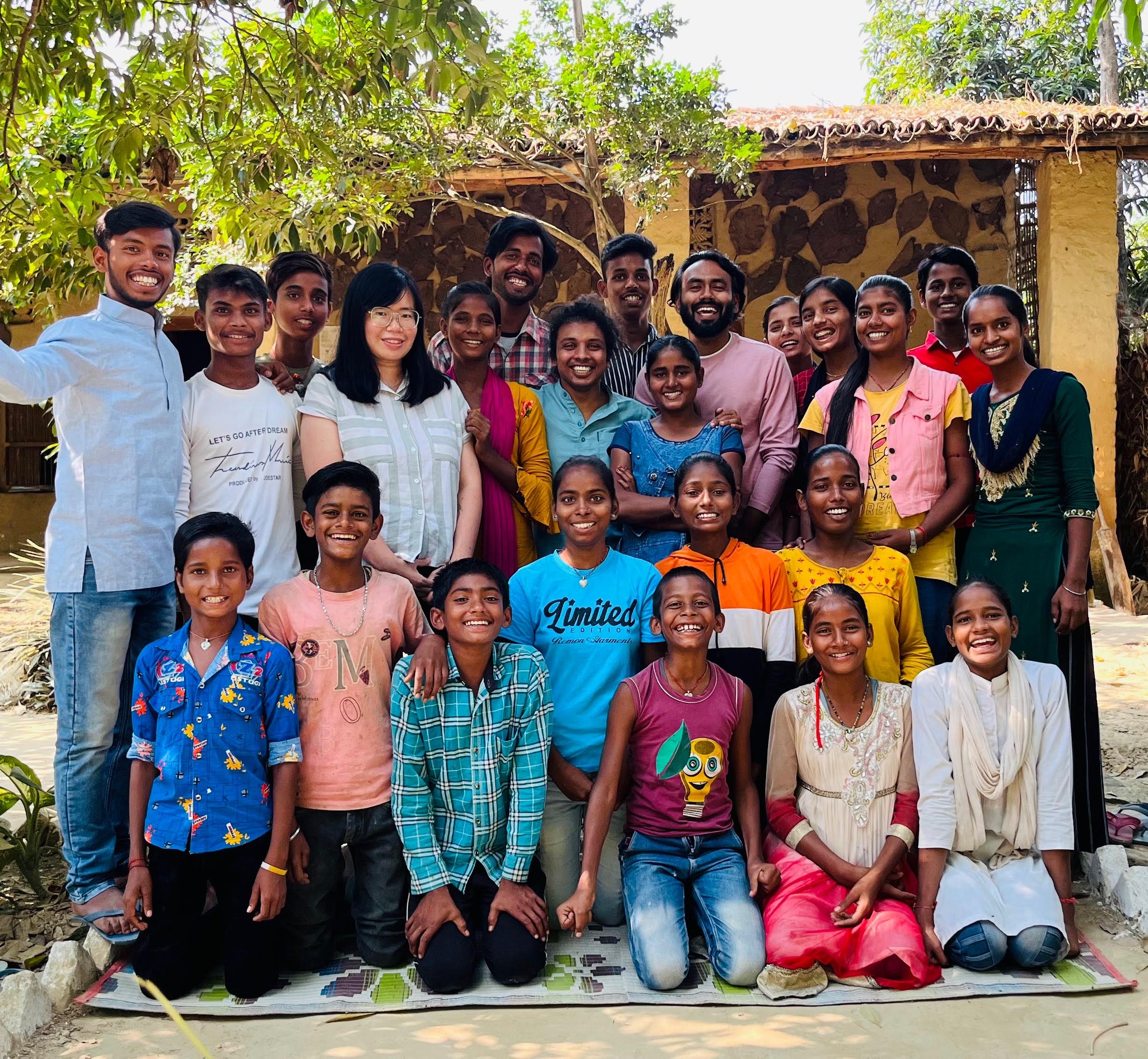 Group of diverse children smiling and learning together in an outdoor classroom setting with trees in background
